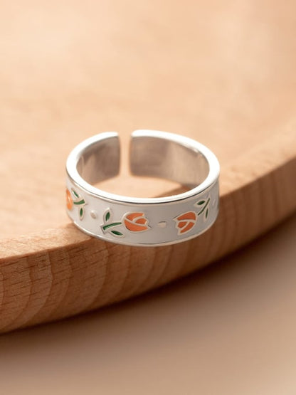 Sterling silver band ring with orange and green tulip flowers on a white enamel setting