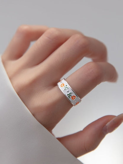 Orange tulip enamel band ring worn on a woman's index finger