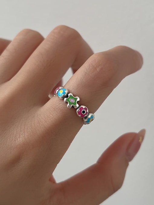 Enamel flower ring worn on a woman's index finger