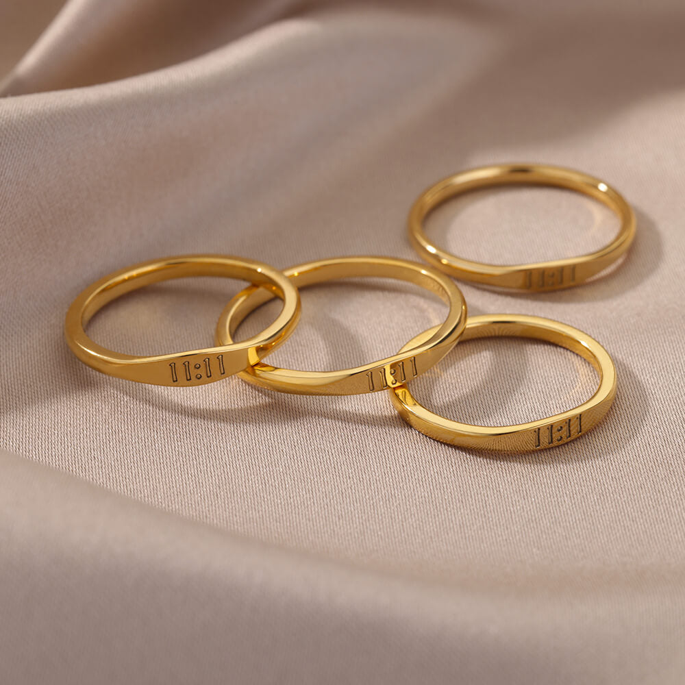 Four gold-plated 11:11 signet rings in a pile